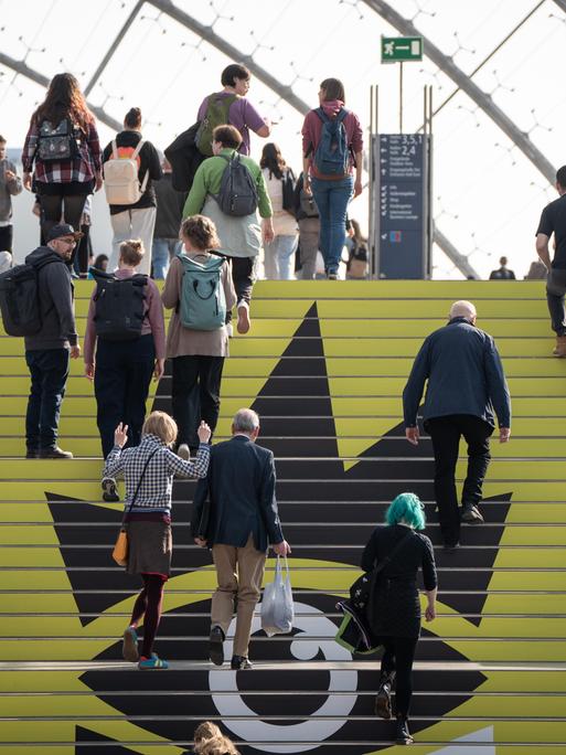 Blick auf die Leipziger Buchmesse am ersten Messetag: Zahlreiche Personen gehen eine Treppe nach oben.