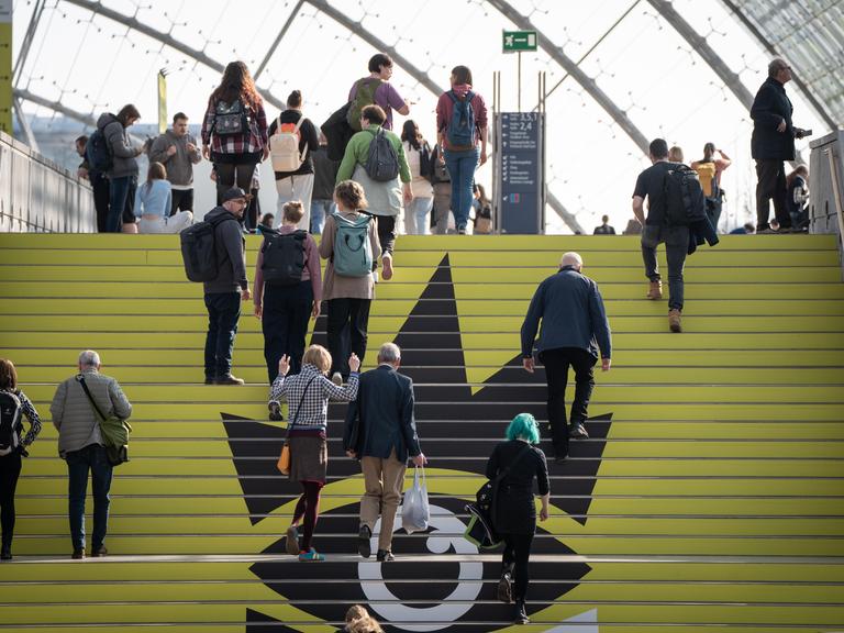 Blick auf die Leipziger Buchmesse am ersten Messetag: Zahlreiche Personen gehen eine Treppe nach oben.