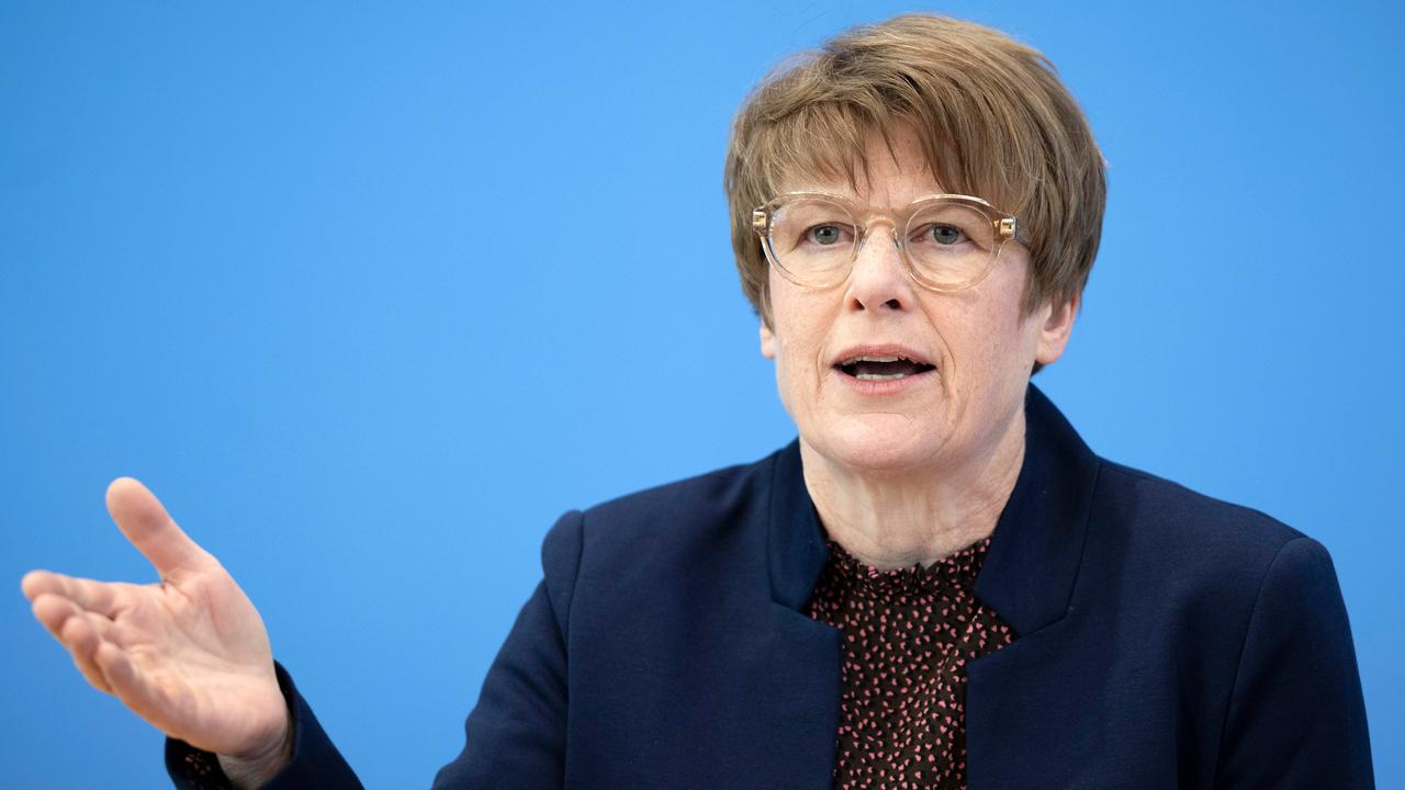 Grimm mit brauner Kurzhaarfrisur und Brille redet auf eine Pressekonferenz. 