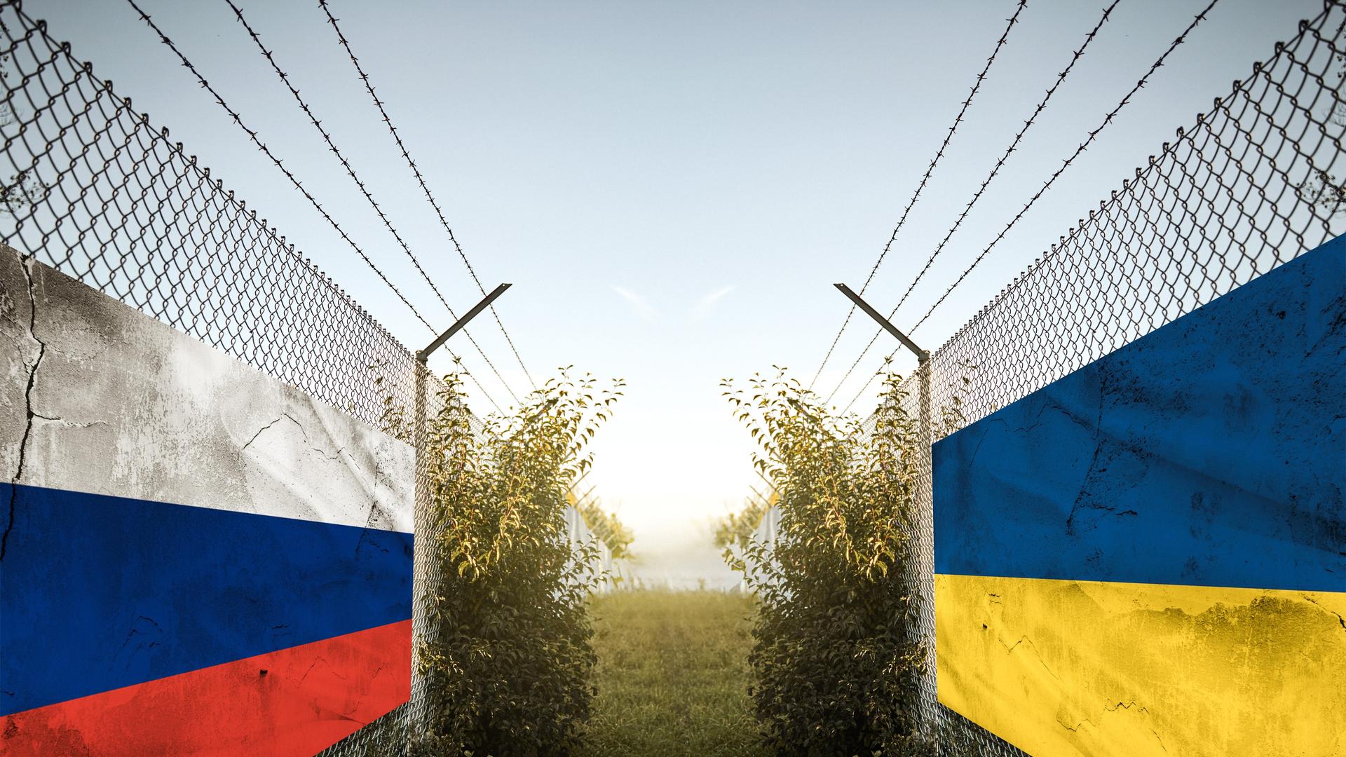 Ukraine und Russland Länder-Fahnen auf einem Zaun an einer Grenze. Symbolbild für Konflikt, Streit und Debatten, symbolisch dargestellt mit russische und ukrainische Flagge und militärischer Stimmung im Grenzgebiet wie im Krieg. FOTOMONTAGE