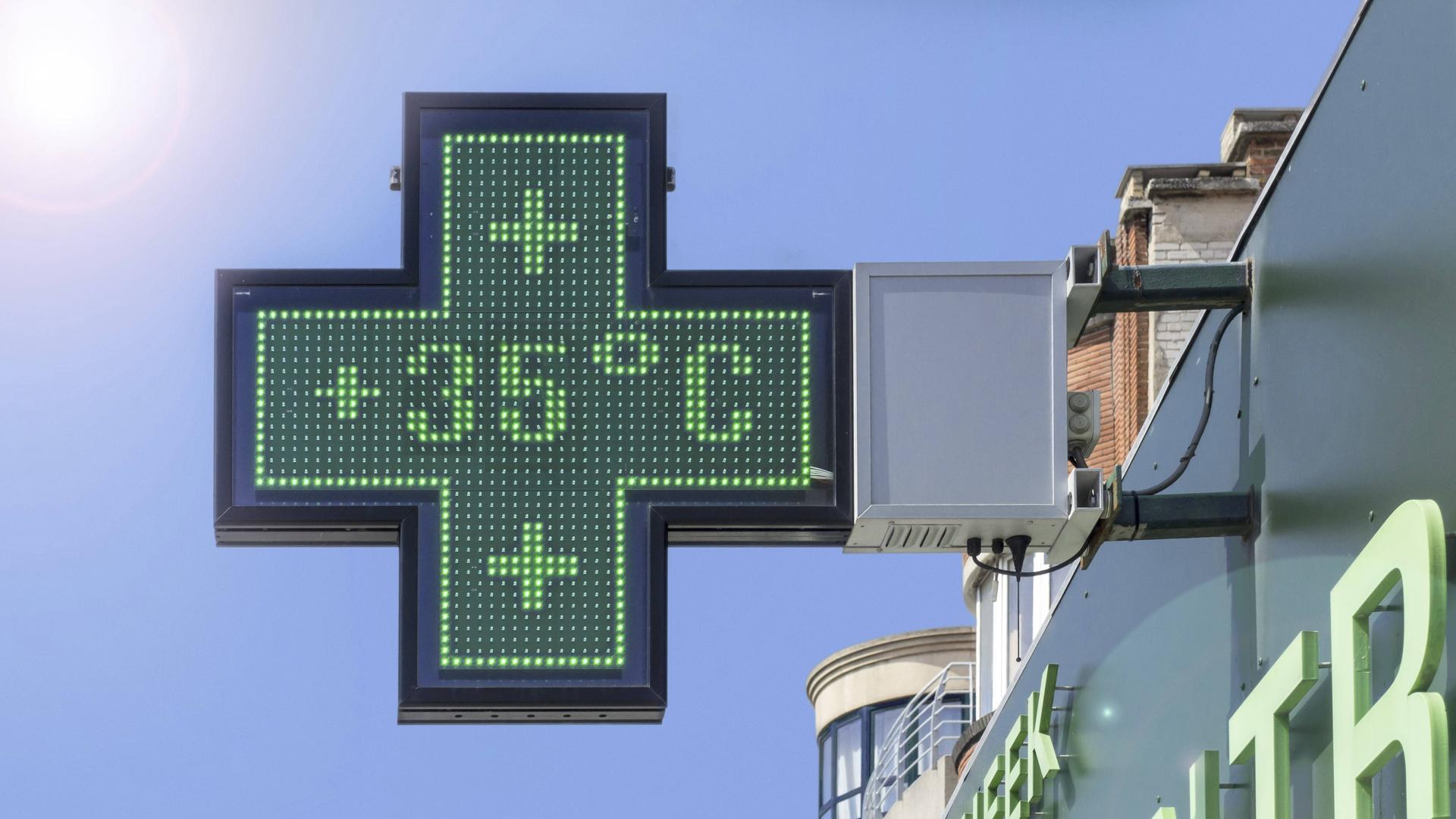 Auf dem kreuzförmigen Schild einer Apotheke zeigt ein Thermometer 35 Grad Celsius an.
