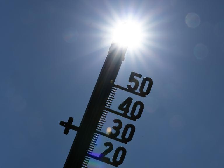 Vor dem Licht der gleißenden Mittagssonne zeichnet sich die Silhouette eines Thermometers ab. Vor dem Licht der gleißenden Mittagssonne zeichnet sich die Silhouette eines Thermometers ab.