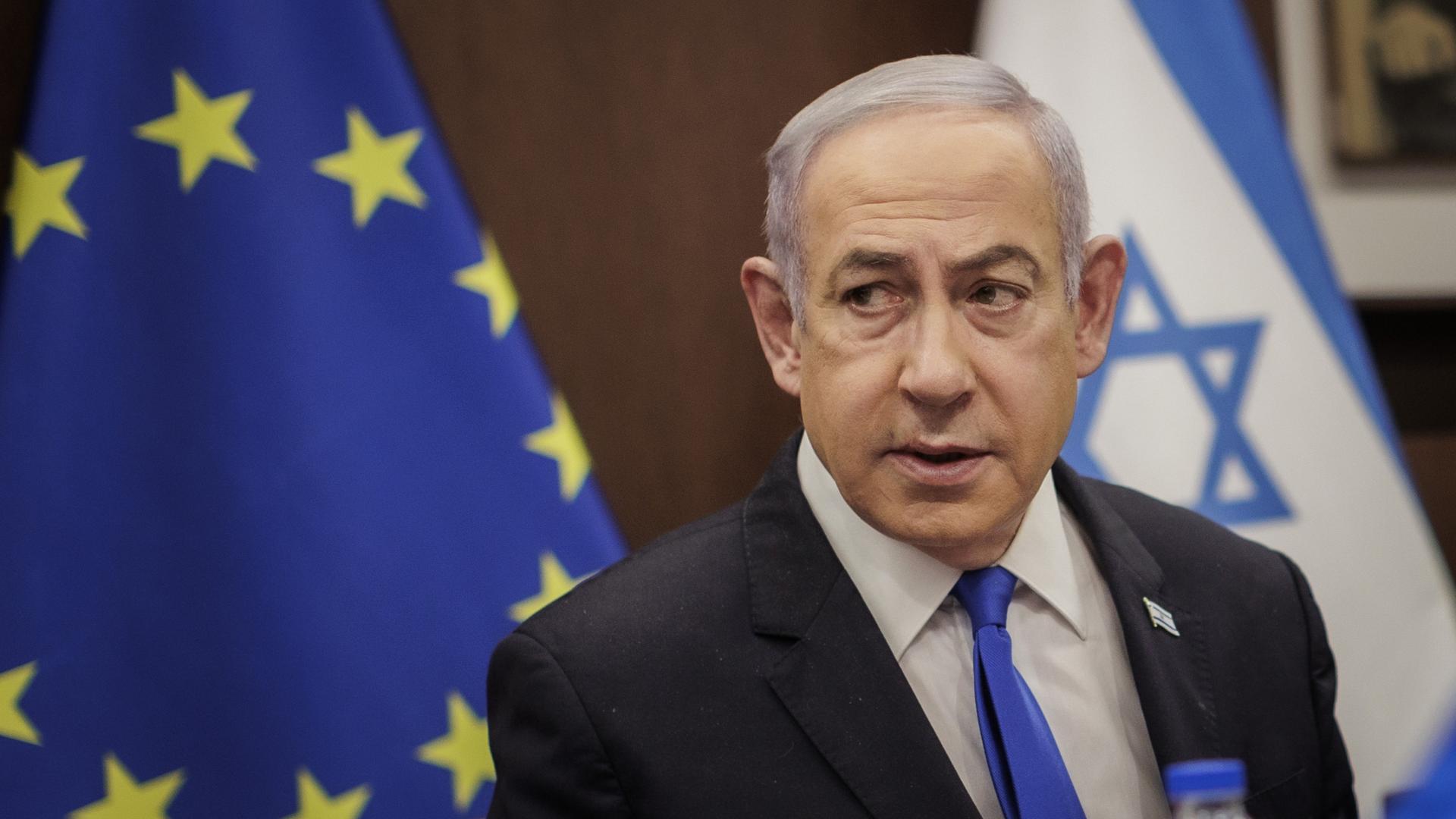 Israels Premier Benjamin Netanjahu. Hinter ihm Flaggen der EU und Israel.