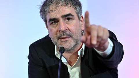 Deniz Yücel zeigt mit dem Finger in Richtung Mitglieder.