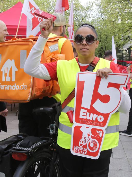 Bei einer Streikaktion der Lieferandofahrer in Dortmund hält eine Frau ein Plakat mit der Aufschrift "15 Euro".