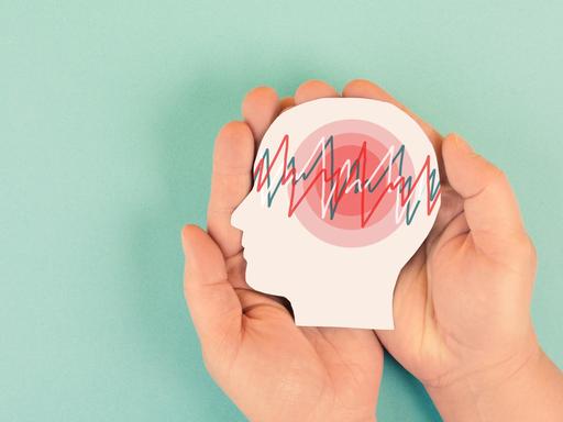 Illsutration: Auf einen Gehrin sind die Kurven eines Gehirnscans zu sehen. Über das Gehirn werden schützend Hände gehalten. 