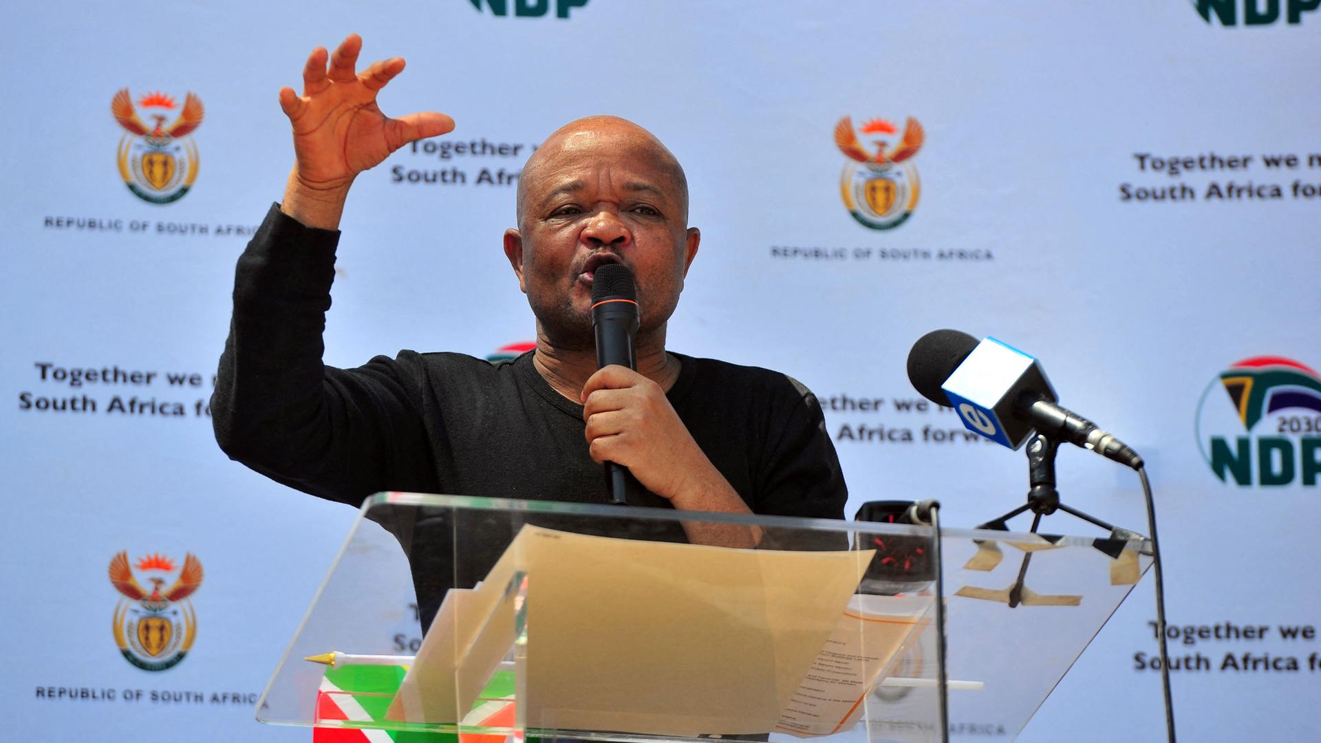 Südafrikas Polizeiminister Senzo Mchunu auf einer Veranstaltung in Pretoria im September 2019. Er hält ein Mikrofon in der Hand und gestikuliert.
