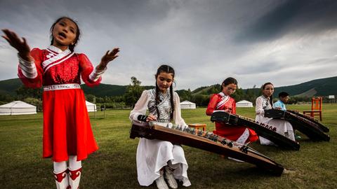 Eine Gruppe junger Mädchen spielt ein Instrument, das einer Zither ähnelt. Es ist die mongolische Zither Yatga. 