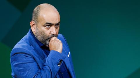 Porträt von Omid Nouripour, Bundesvorsitzender von Bündnis 90/Die Grünen, aufgenommen beim Bundesparteitag von Bündnis 90/ Die Grünen bei der 48. Ordentlichen Bundesdelegiertenkonferenz 2022 in Bonn. Ein mittelalter Mann mit Glatze und Bart in blauem Anzug hält nachdenklich die Hand ans Kinn.
