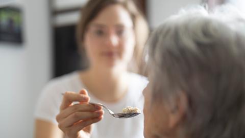 Einer älteren Frau wird Essen gereicht.