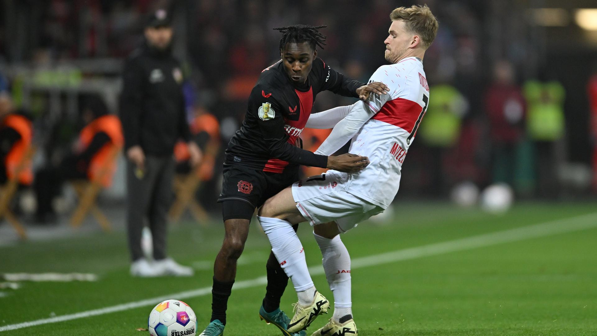 Das Bild zeigt zwei Fußballspieler. Es handelt sich um Leverkusens Jeremie Frimpong und Stuttgarts Maximilian Mittelstädt. Sie kämpfen um den Ball.