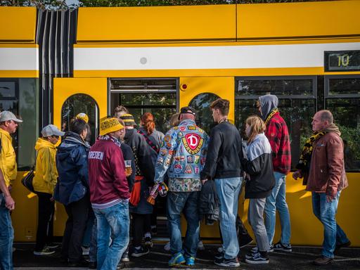 Fans von Dynamo Dresden warten nach einem Spiel an der Haltestelle auf die Bahn. 