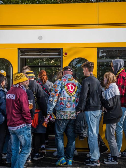 Fans von Dynamo Dresden warten nach einem Spiel an der Haltestelle auf die Bahn. 