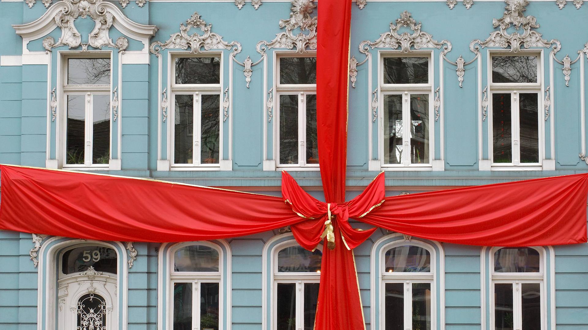Ein als Geschenk mit einer großen roten Schleife dekoriertes historisches Bürgerhaus