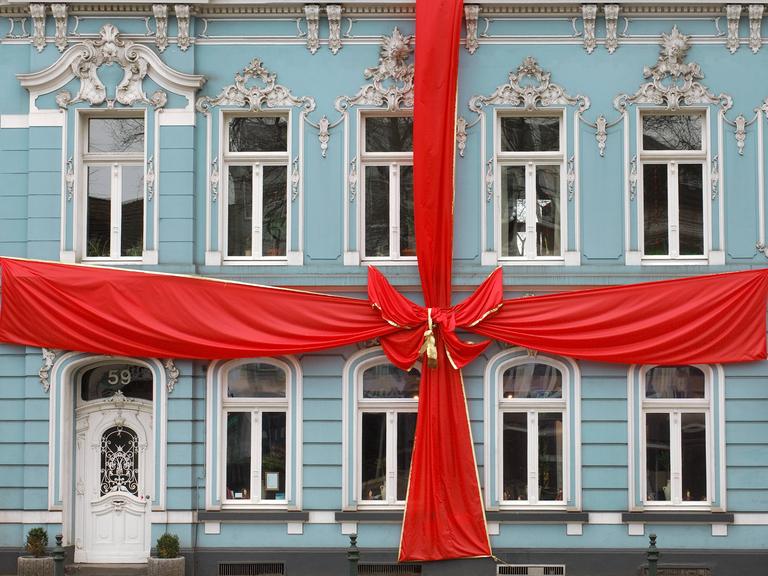 Ein als Geschenk mit einer großen roten Schleife dekoriertes historisches Bürgerhaus