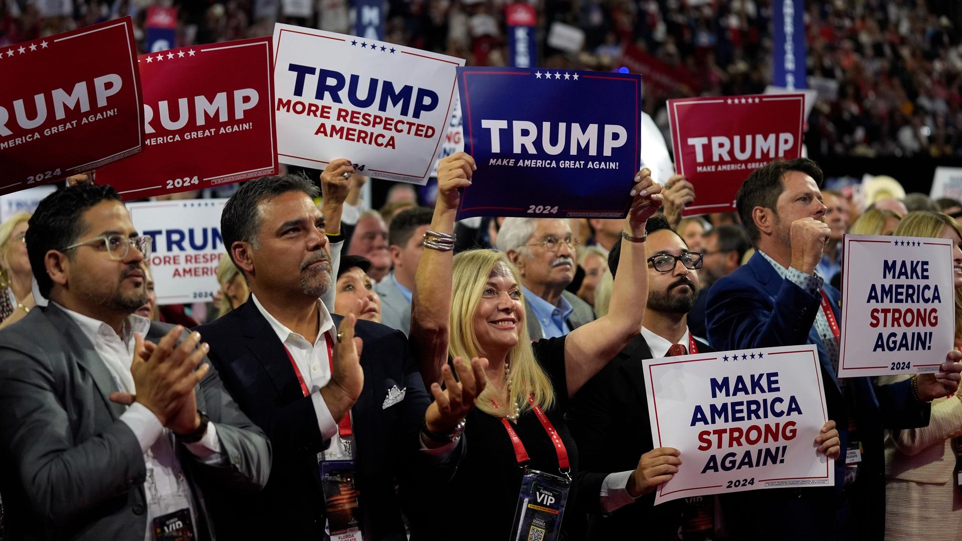 Anhänger hören Donald Trump bei einer Rede der Republican National Convention in Milwaukee zu. Einige halten Plakate in weiß, rot und blau mit der Aufschrift "Trump" hoch.