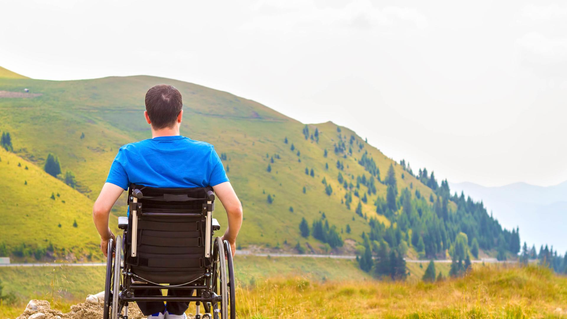 Ein Rollstuhlfahrer blickt auf einen Berg