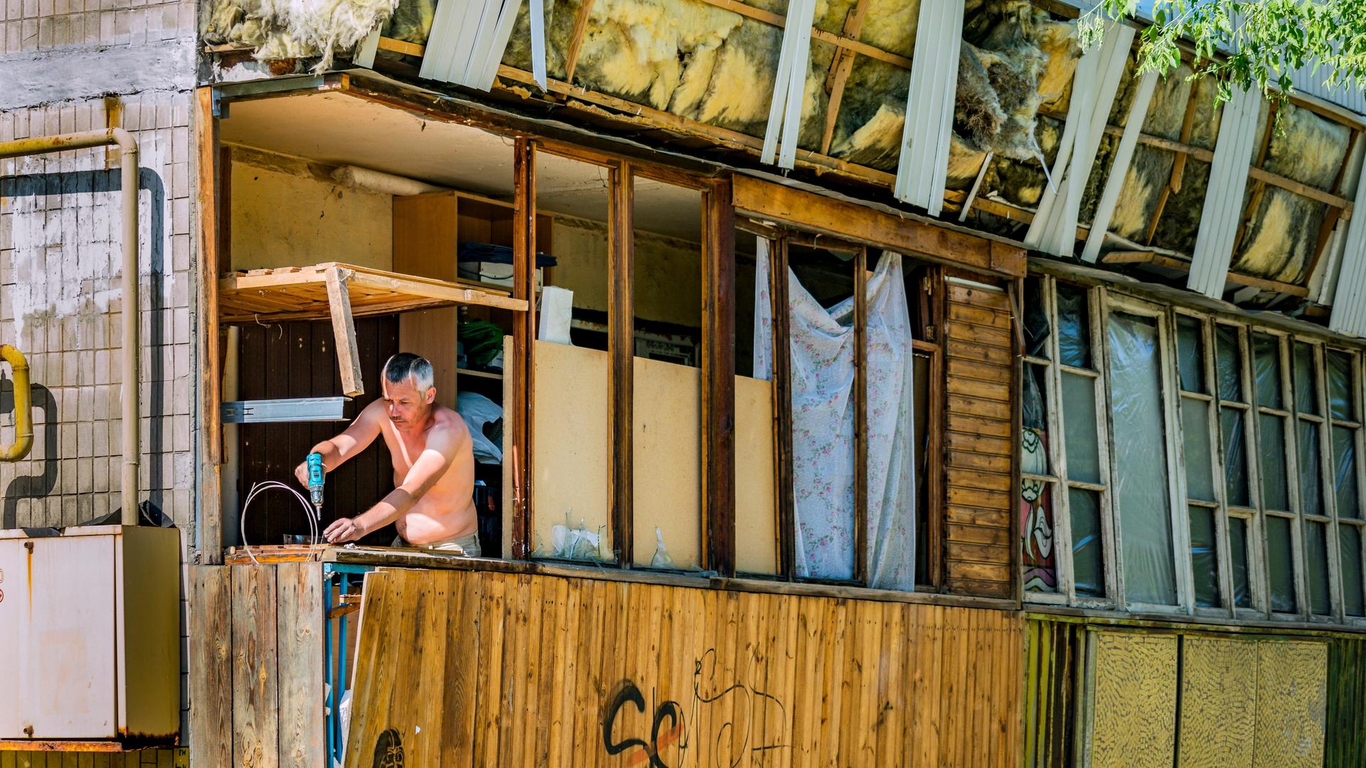Ein Mann repariert nach einem russischen Luftangriff den Balkon seines Hauses 
