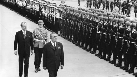 Willy Brandt (l.) und Leonid Breschnew. Zwei ältere Männer laufen eine Militärparade ab.