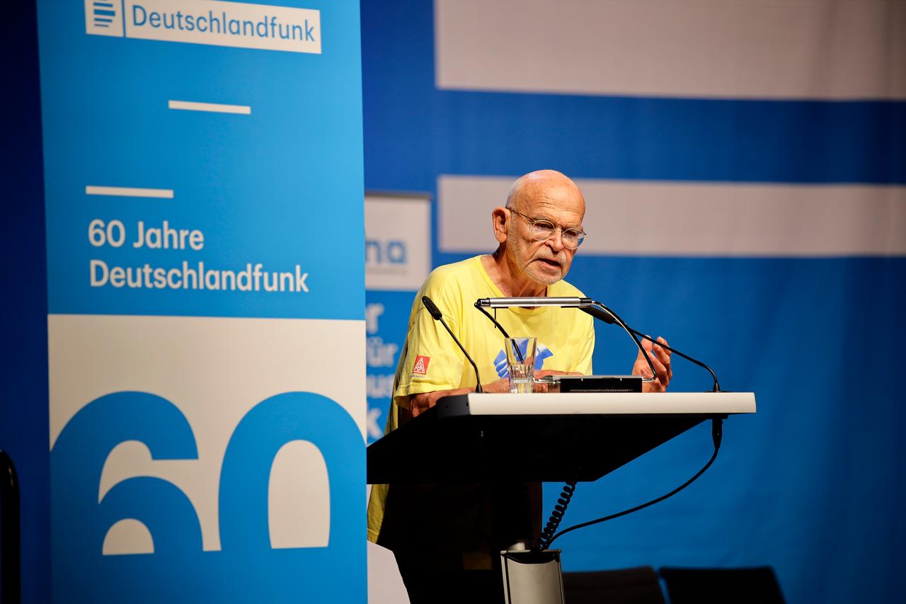 Günter Wallraff spricht beim Kölner Forum für Journalismuskritik in ein Mikrofon auf der Bühne