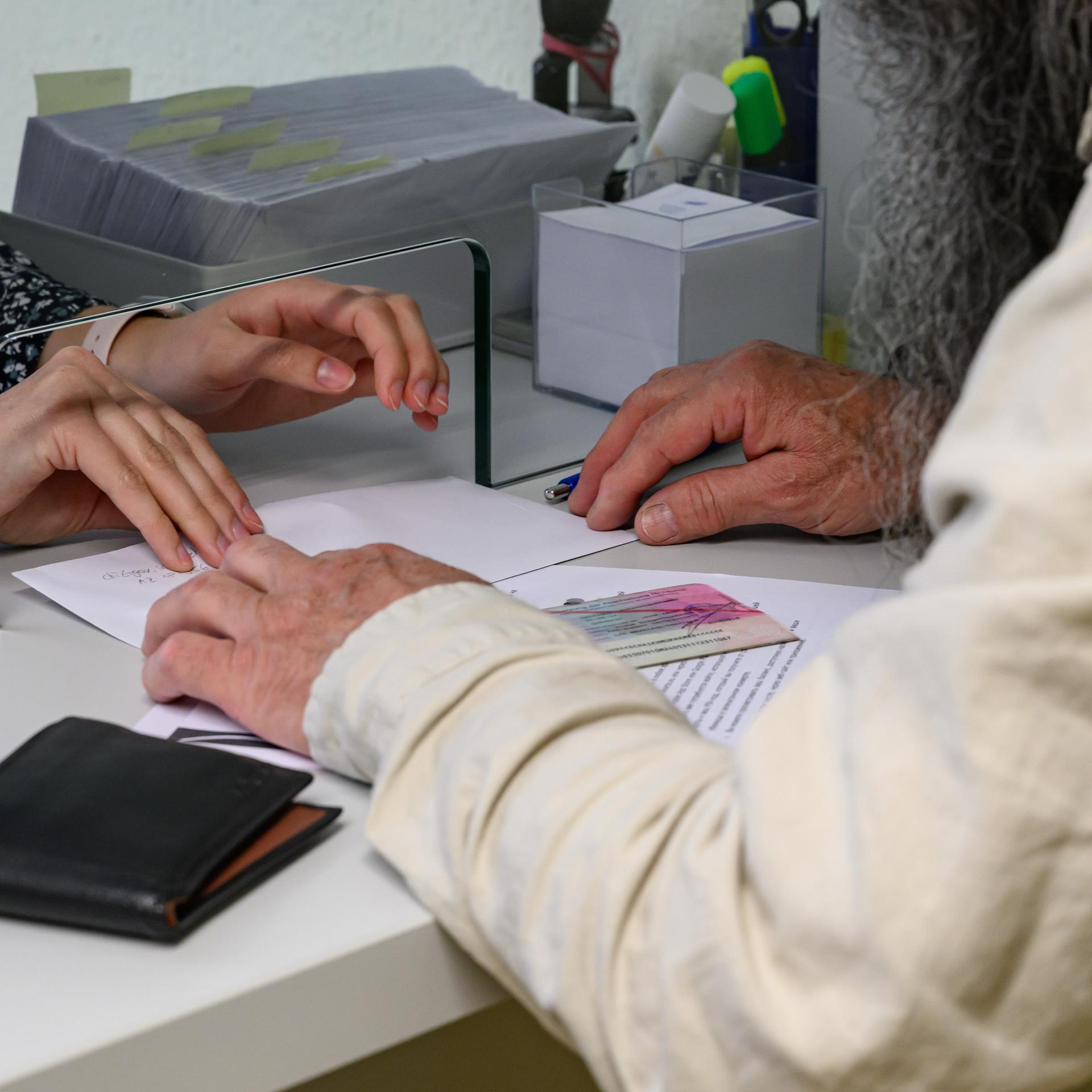 Ein Asylbewerber erhält in einem Umschlag seine Bezahlkarte von einer Mitarbeiterin in einer Außenstelle des Sozialamtes vom Landkreis Märkisch-Oderland. Asylbewerber sollen künftig einen Teil staatlicher Leistungen als Guthaben via Bezahlkarte erhalten.