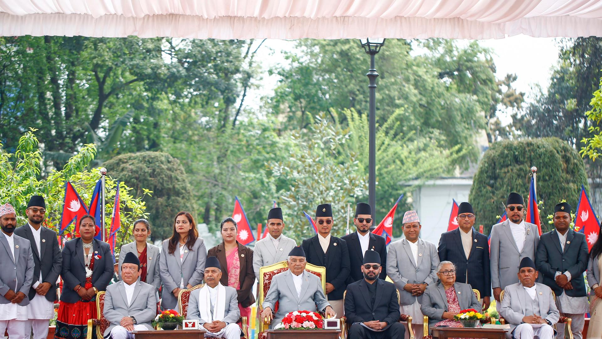 Shah sitzt mit anderen Regierungsmitgliedern in einer Reihe, dahinter stehen noch mehrere neue Mitglieder des Kabinetts. Shah sitzt mit anderen Regierungsmitgliedern in einer Reihe, dahinter stehen noch mehrere neue Mitglieder des Kabinetts.