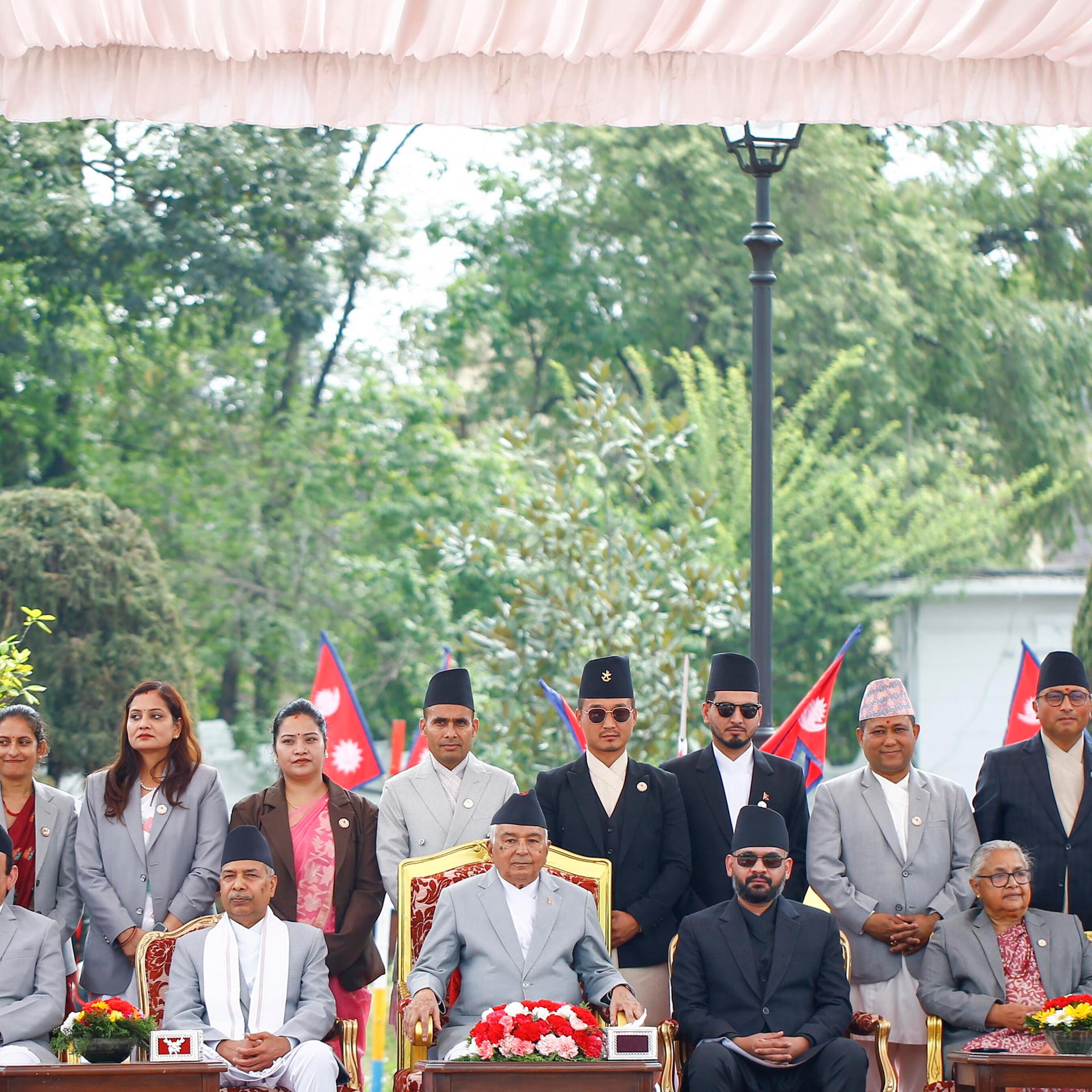 Shah sitzt mit anderen Regierungsmitgliedern in einer Reihe, dahinter stehen noch mehrere neue Mitglieder des Kabinetts.