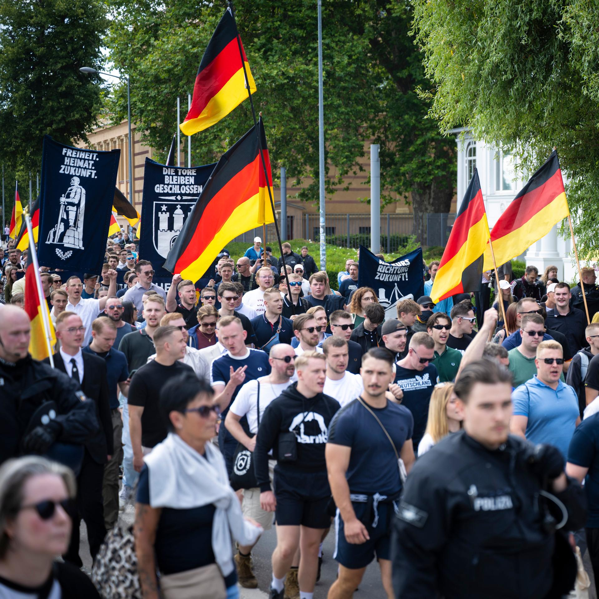 Demo-Teilnehmer der AfD-Jugendorganisation Generation Deutschland ziehen durch die Schweriner Innenstadt. Viele von ihnen tragen Deutschlandfahnen.