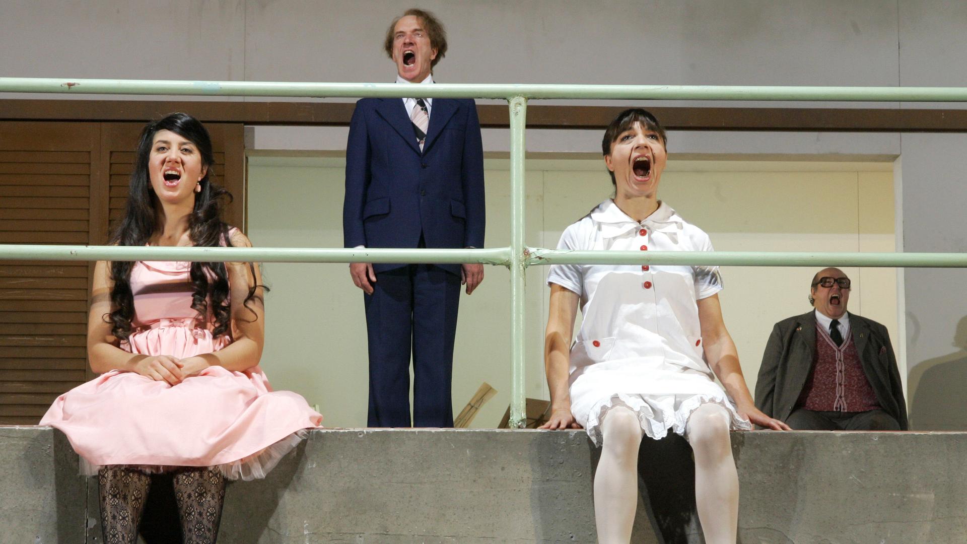 Zwei Schauspielerinnen und zwei Schauspieler stoßen auf einer Bühne während einer Probe einen langezogenen Schrei aus.