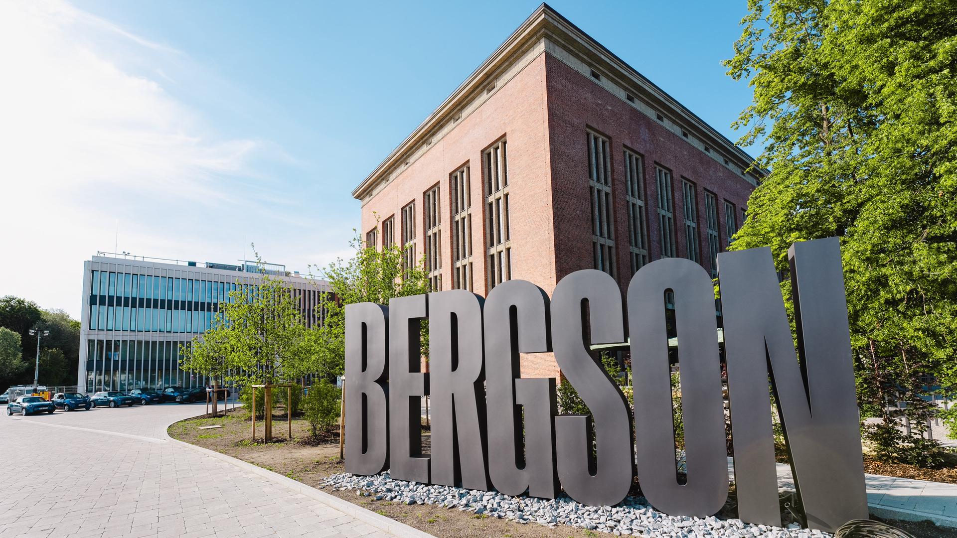 Blick auf einen roten Backsteinbau, vor dem ein großer, silbergrauer Buchstabenzug "Bergson" steht.