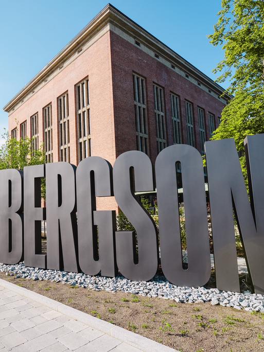 Blick auf einen roten Backsteinbau, vor dem ein großer, silbergrauer Buchstabenzug "Bergson" steht.