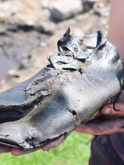 Ein alter römischer Schuh wird in die Kamera gehalten.