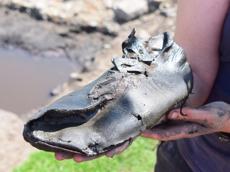 Ein alter römischer Schuh wird in die Kamera gehalten.