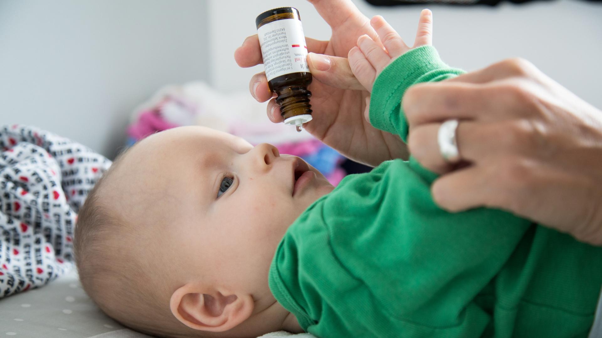 Eine Mutter verabreicht ihrem sechs Monate alten Baby Vitamin-D-Tropfen (gestellte Szene). 