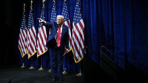 Donald Trump steht auf einer Bühne vor US-Flaggen und zeigt mit ausgestrecktem Arm und Zeigefinger ins Publikum.