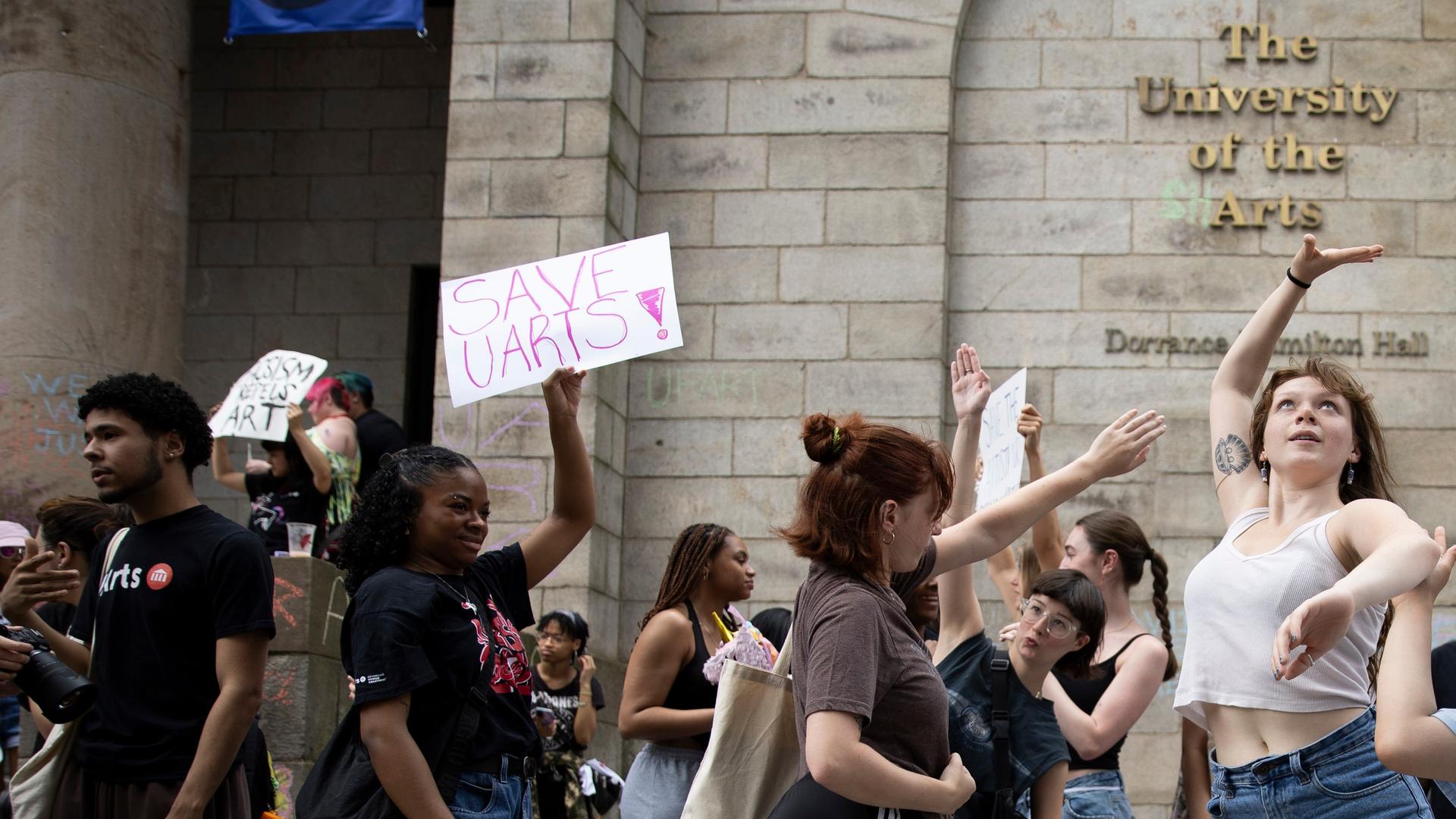 Studierende tanzen vor dem Gebäude der University of the Arts in Philadelphia, andere halten Schilder mit der Aufschrift "Save U Arts" hoch, also in etwa "Rettet die Uni der Künste". Studierende tanzen vor dem Gebäude der University of the Arts in Philadelphia, andere halten Schilder mit der Aufschrift "Save U Arts" hoch, also in etwa "Rettet die Uni der Künste".