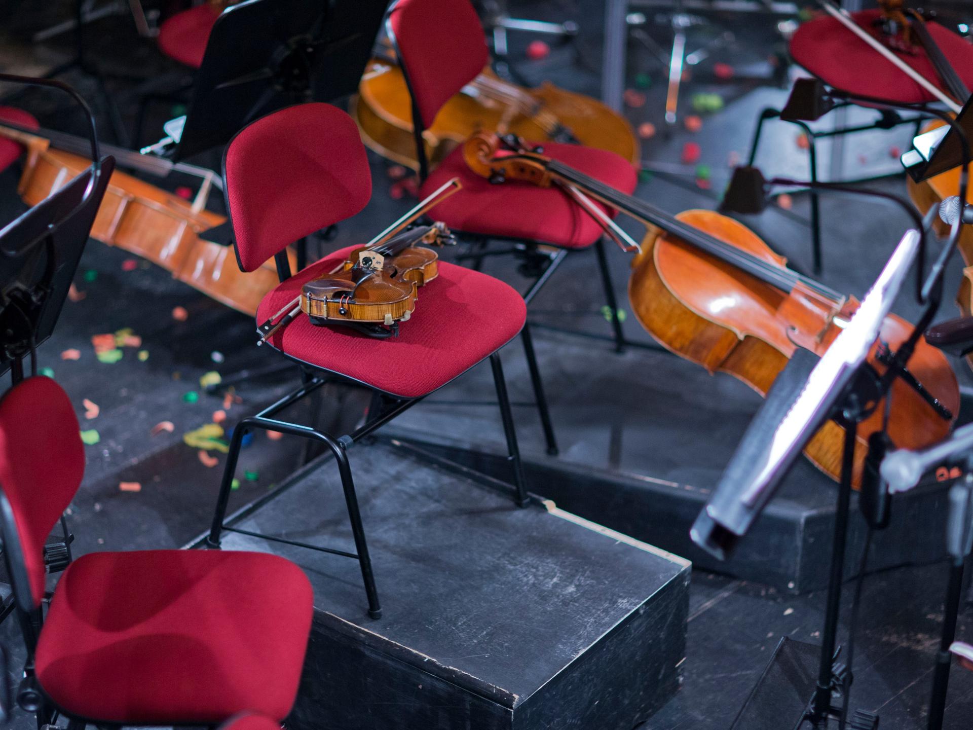 Instrumente liegen während der Probenpause eines Orchestern auf Stühlen in einem Orchestergraben.