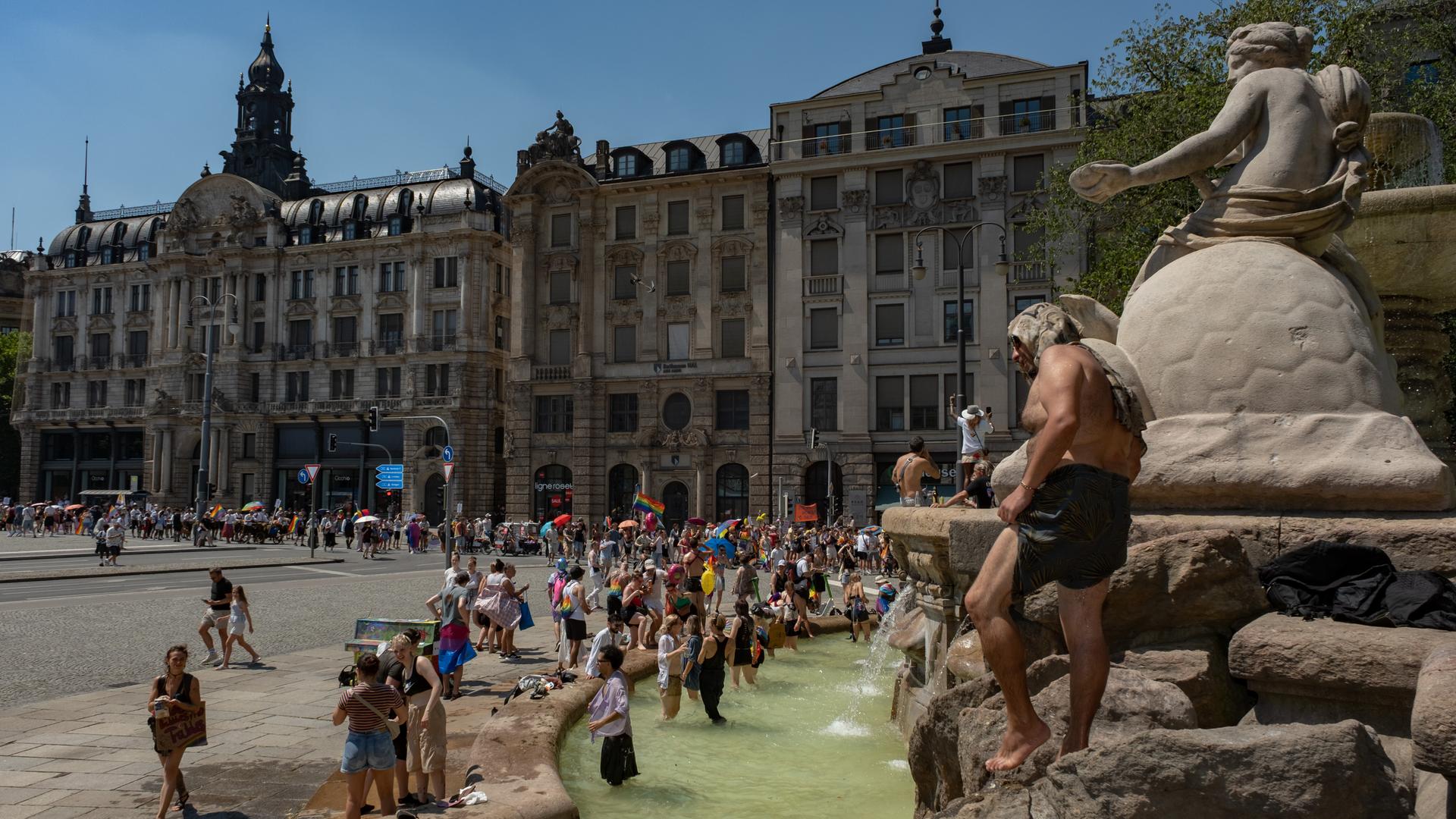 CSD Parade in München. Teilnehmerinnen kühlen sich im Brunnen ab.