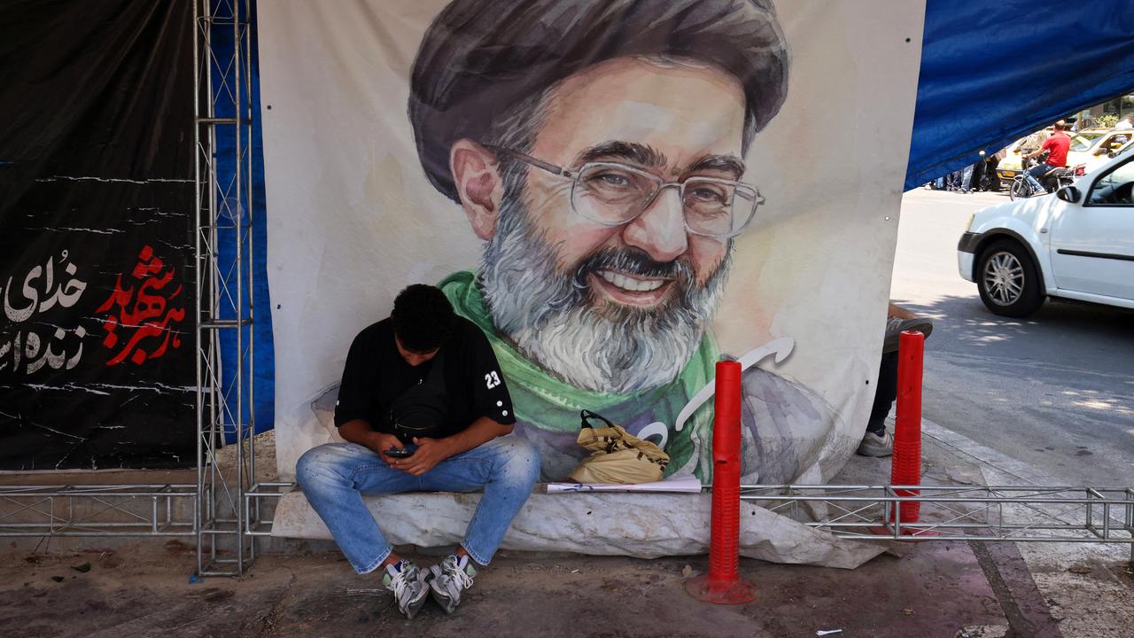 Ein Mann sitzt am 10. Juni 2026 auf dem Vanak-Platz in Teheran vor einem Plakat mit dem Porträt des iranischen Obersten Führers Mojtaba Khamenei, er schaut auf sein Mobiltelefon herab. Ein Mann sitzt am 10. Juni 2026 auf dem Vanak-Platz in Teheran vor einem Plakat mit dem Porträt des iranischen Obersten Führers Mojtaba Khamenei, er schaut auf sein Mobiltelefon herab.