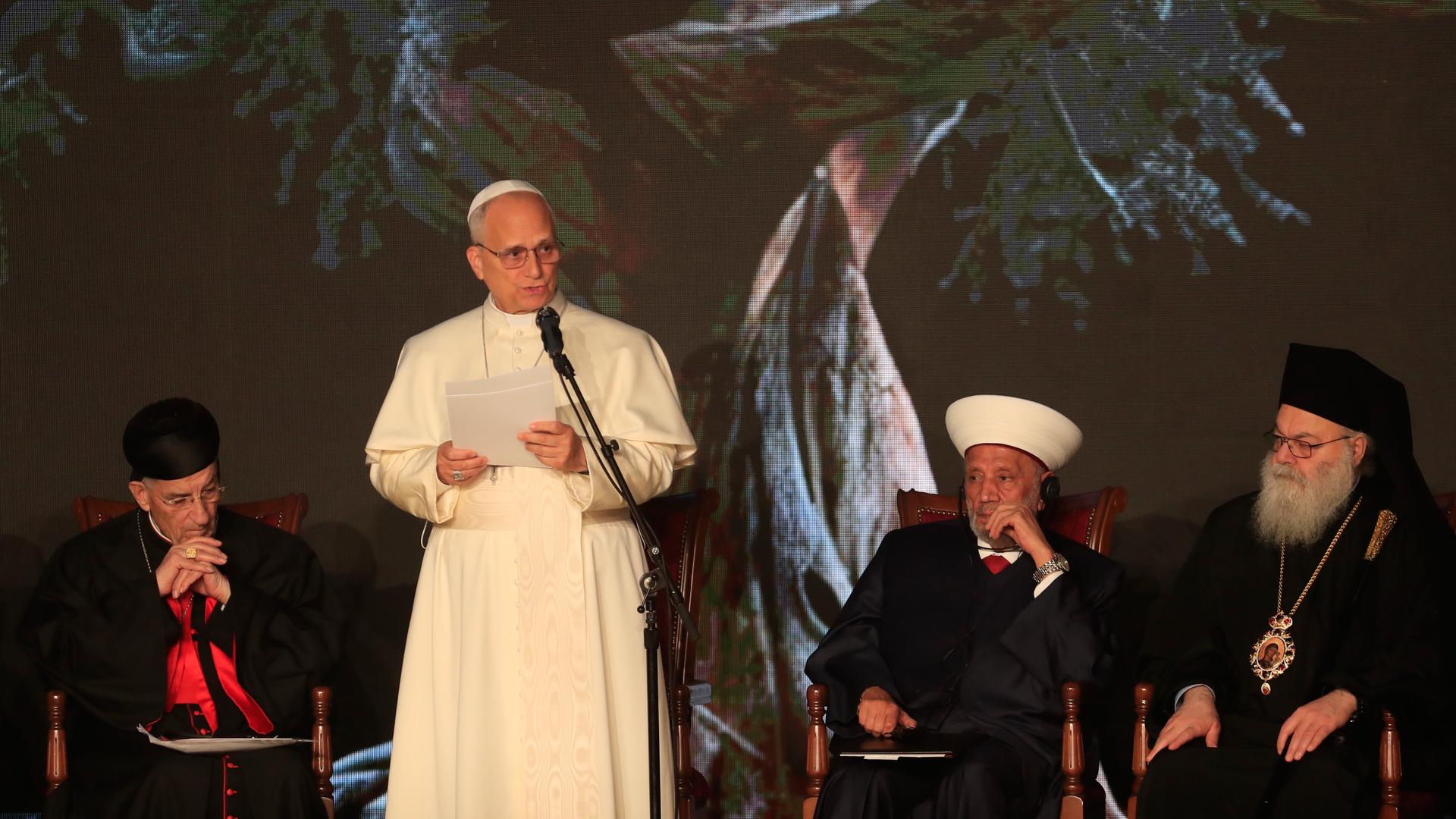 Papst Leo stehend am Mikrofon, hinter ihm sitzen andere religiöse Würdenträger Papst Leo stehend am Mikrofon, hinter ihm sitzen andere religiöse Würdenträger