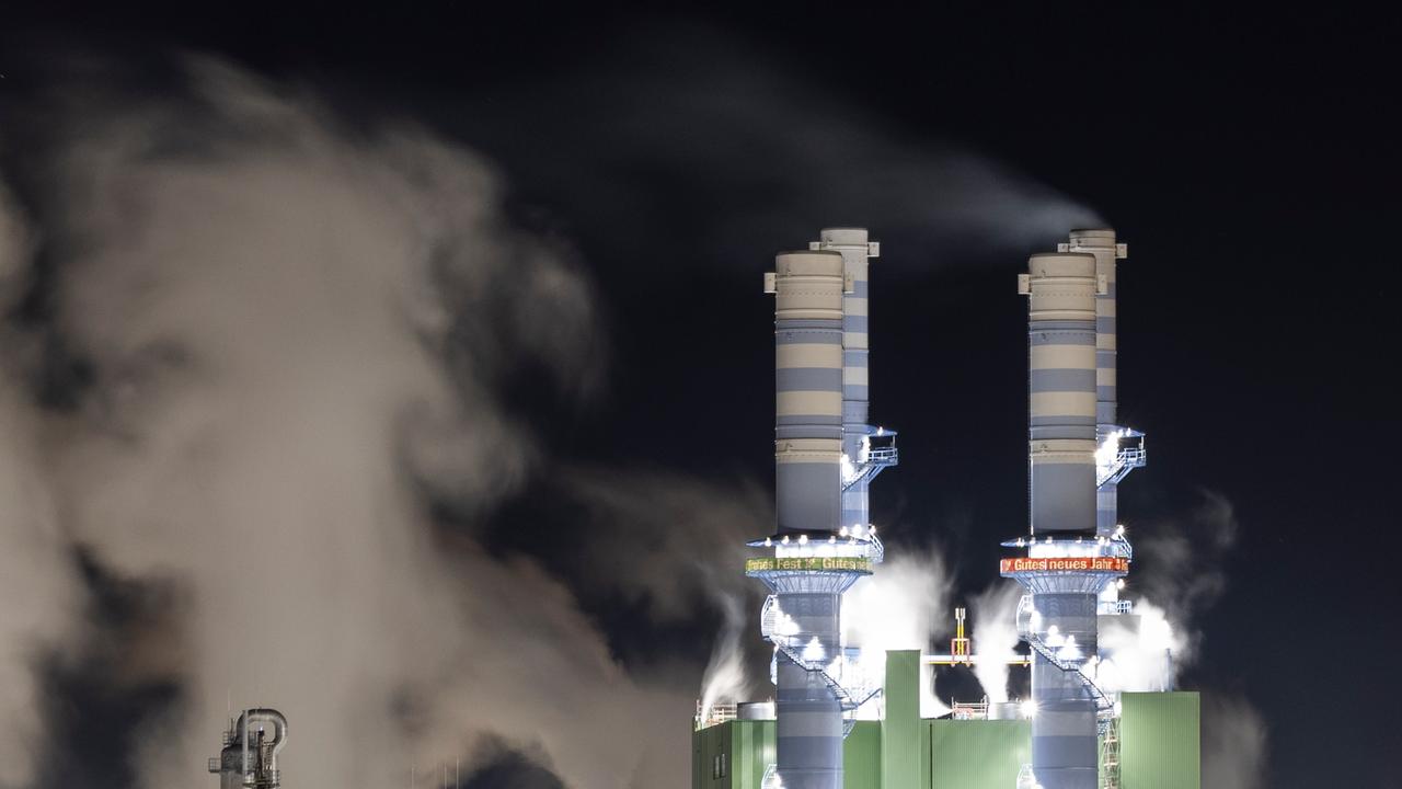 Dampf steigt bei Nacht aus beleuchteten Industrieschornsteinen des Industriepark Höchst auf. 