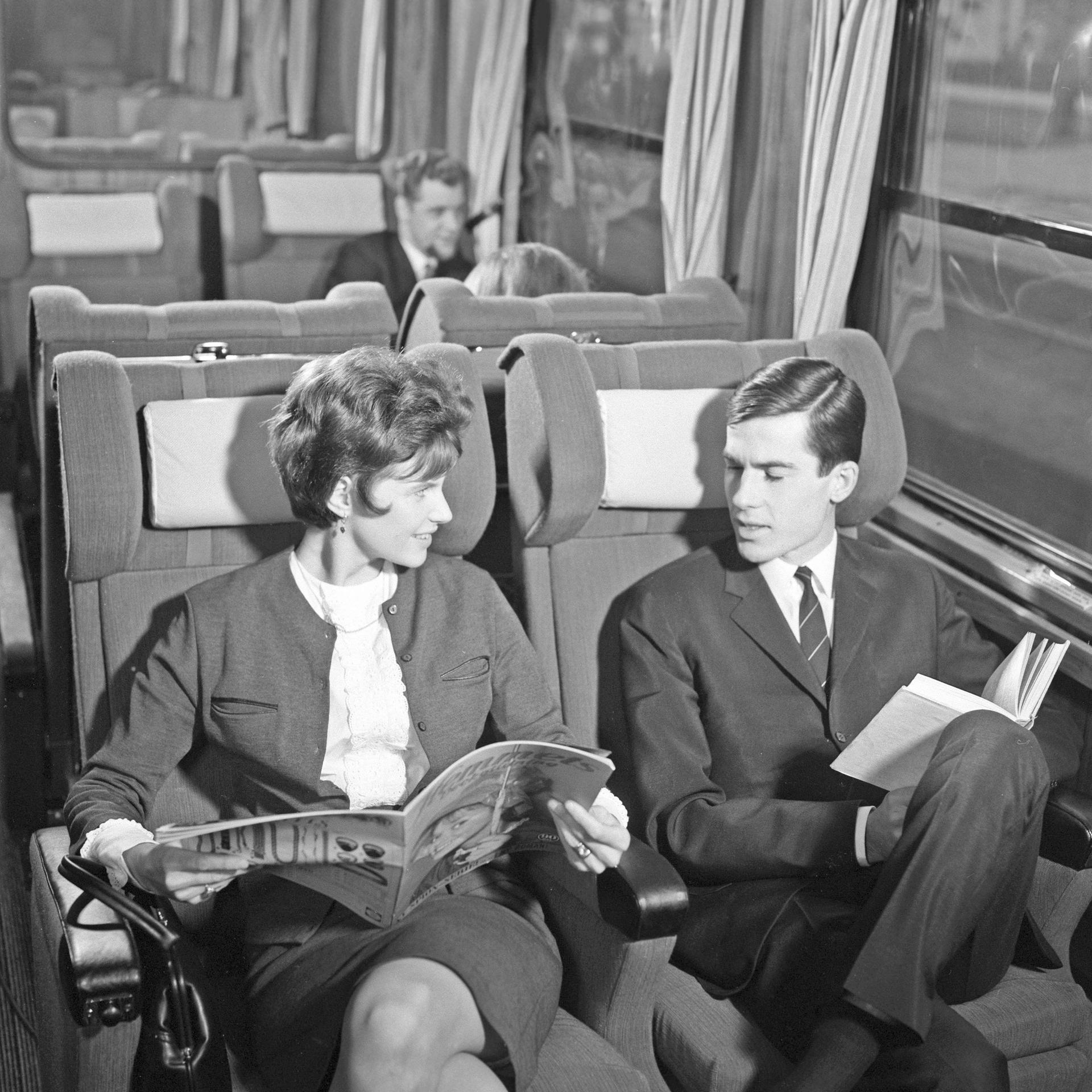 Zugreisen in den 1960er Jahren - ein Paar sitzt im Zug, die Frau eine Zeitschrift, der Mann ein Buch lesend.