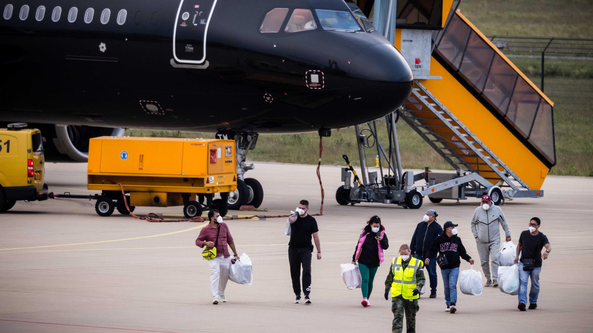 Maskierte Passagiere auf dem Flughafen Eindhoven, wo ein Flugzeug mit Personen von Bord des Kreuzfahrtschiffs "Hondius" gelandet ist. 