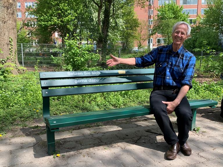 Christoph Busch vom Verein Zuhör-Kiosk e.V. sitzt auf einer grünen Bank in Hamburg Eimsbüttel. Er hatte die Idee für die sogenannten Zuhörbänke. 