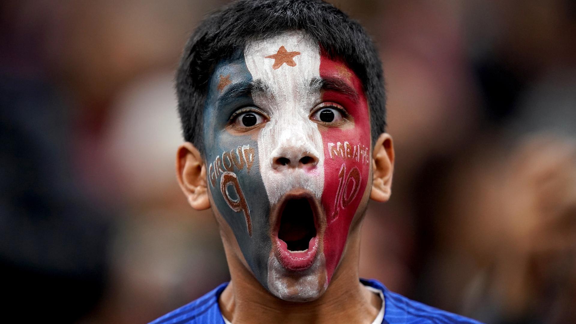 Ein junger Fan jubelt. Sein Gesicht ist mit den Farben der französischen Flagge bemalt.