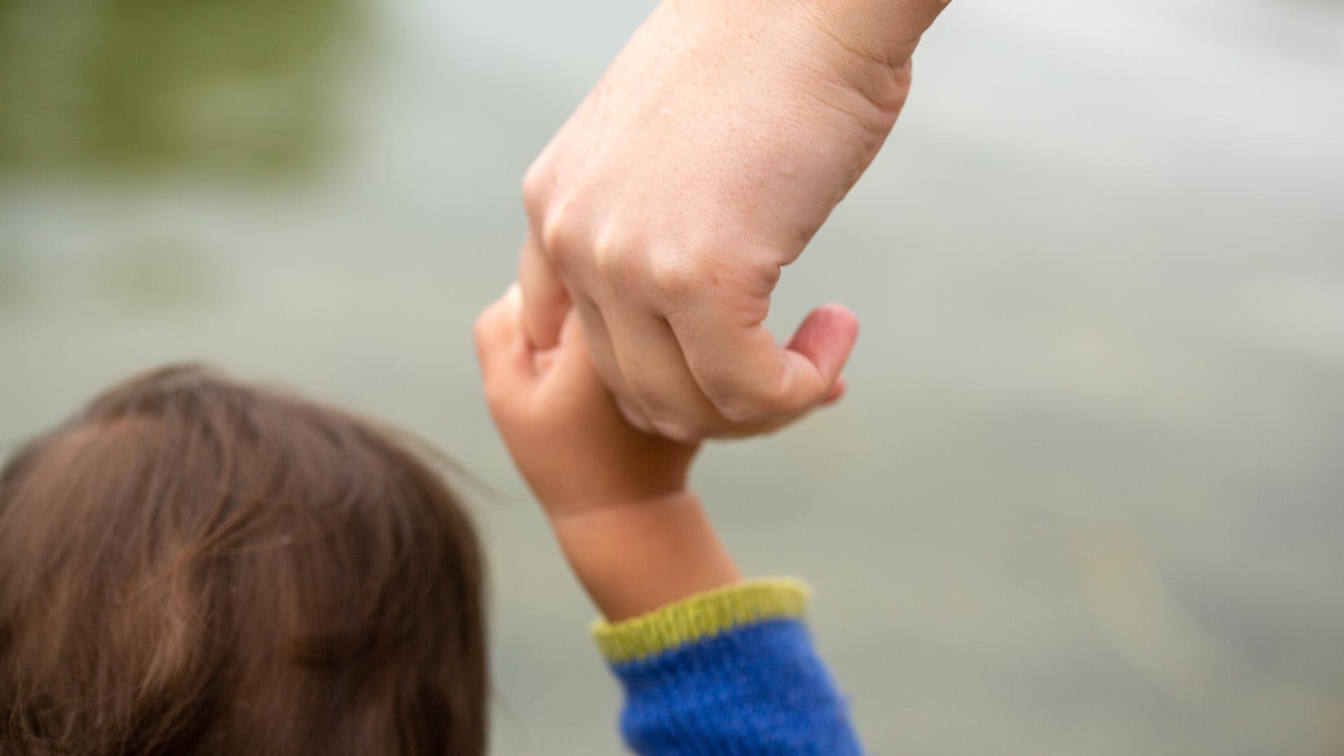 Eine Mutter hält ihr Kind an der Hand. Eine Mutter hält ihr Kind an der Hand.