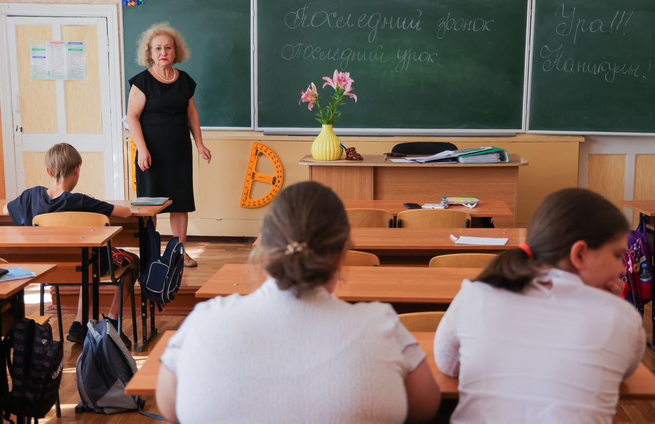 Schülerinnen und Schüler in der Region Donezk feiern mit ihrer Lehrerin das Schuljahresende. 