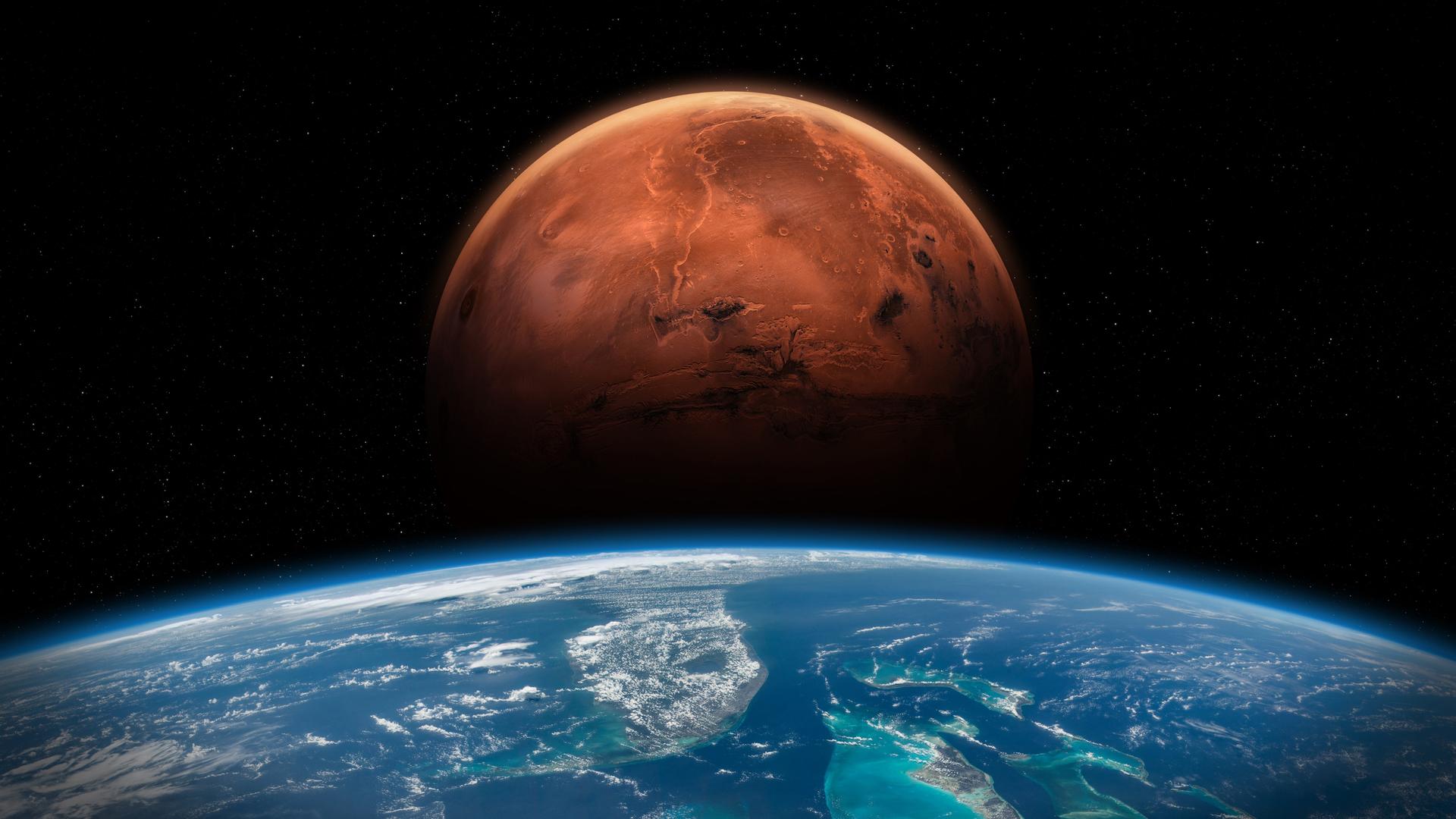 Im Vordergrund die Erde, dahinter erhebt sich der rote Mars vor schwarzem Hintergrund