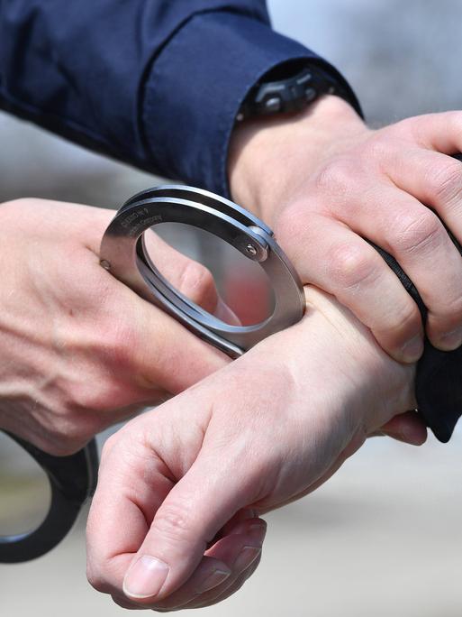 Ein Polizist legt Handschellen an bei einer Festnahme.