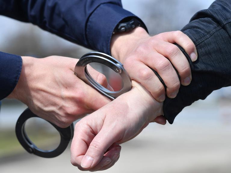 Ein Polizist legt Handschellen an bei einer Festnahme.